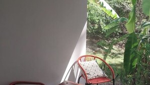 Un balcón con dos sillas, una con un cojín estampado y otra con un cojín liso.