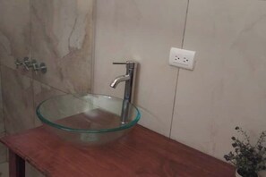 A bathroom with a glass bowl sink, a wooden countertop, a marble wall, and a power outlet. - Comfortable and cozy refuge in the middle of the tropical jungle (Estrada)