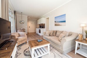 Een moderne woonkamer met een bank, salontafel en een eethoek met stoelen.