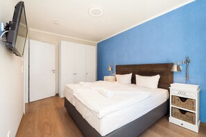 Hotelkamer met een bed, een aan de muur bevestigde televisie, een kledingkast, een nachtkastje met een lamp en een bedtafel met een lamp.