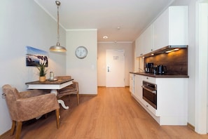 Une cuisine moderne avec des meubles blancs, un plan de travail en bois et un four encastré.