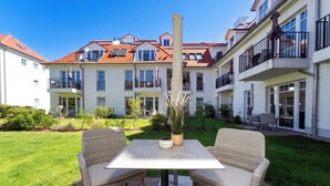 Ein Innenhof mit Tisch und Stühlen, umgeben von Gebäuden mit Balkonen und Fenstern.