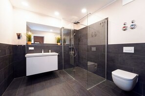A modern bathroom with a glass-enclosed shower, a white bathtub, and a toilet. - Baltischer Hof apartment 10 (Ostseebad Boltenhagen)