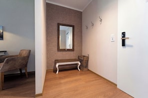 A room with a wooden bench, a wall-mounted mirror, a door with a handle, and a small basket. - Baltischer Hof apartment 10 (Ostseebad Boltenhagen)