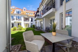 Ein Innenhof mit Tisch und Stühlen, einem Blumentopf und Blick auf ein mehrstöckiges Gebäude mit Balkonen.