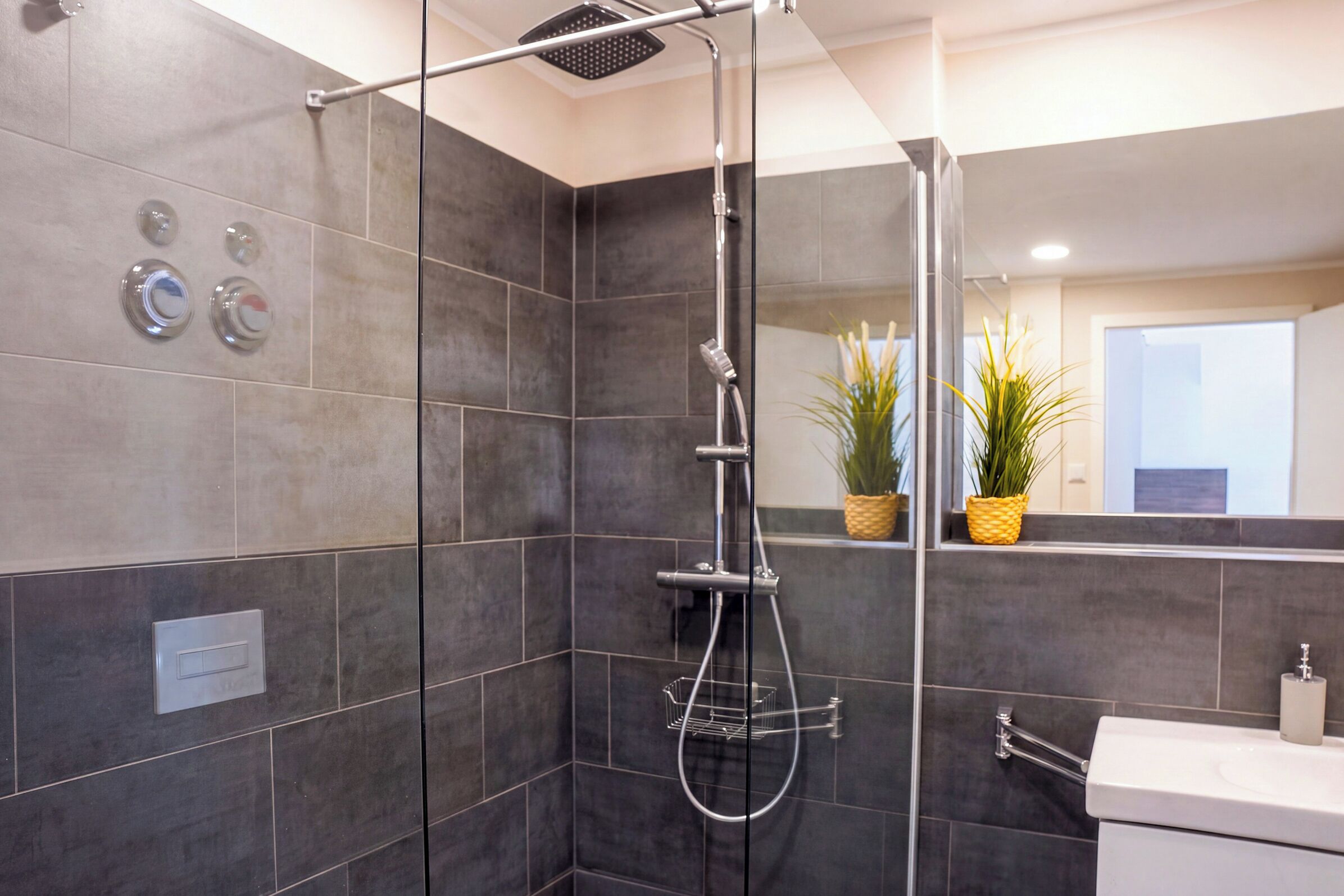 A modern bathroom with a shower, a toilet, and a sink.