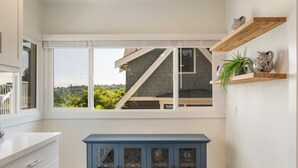 Uma cozinha com vista para uma casa, um armário azul e prateleiras de madeira com objetos decorativos.