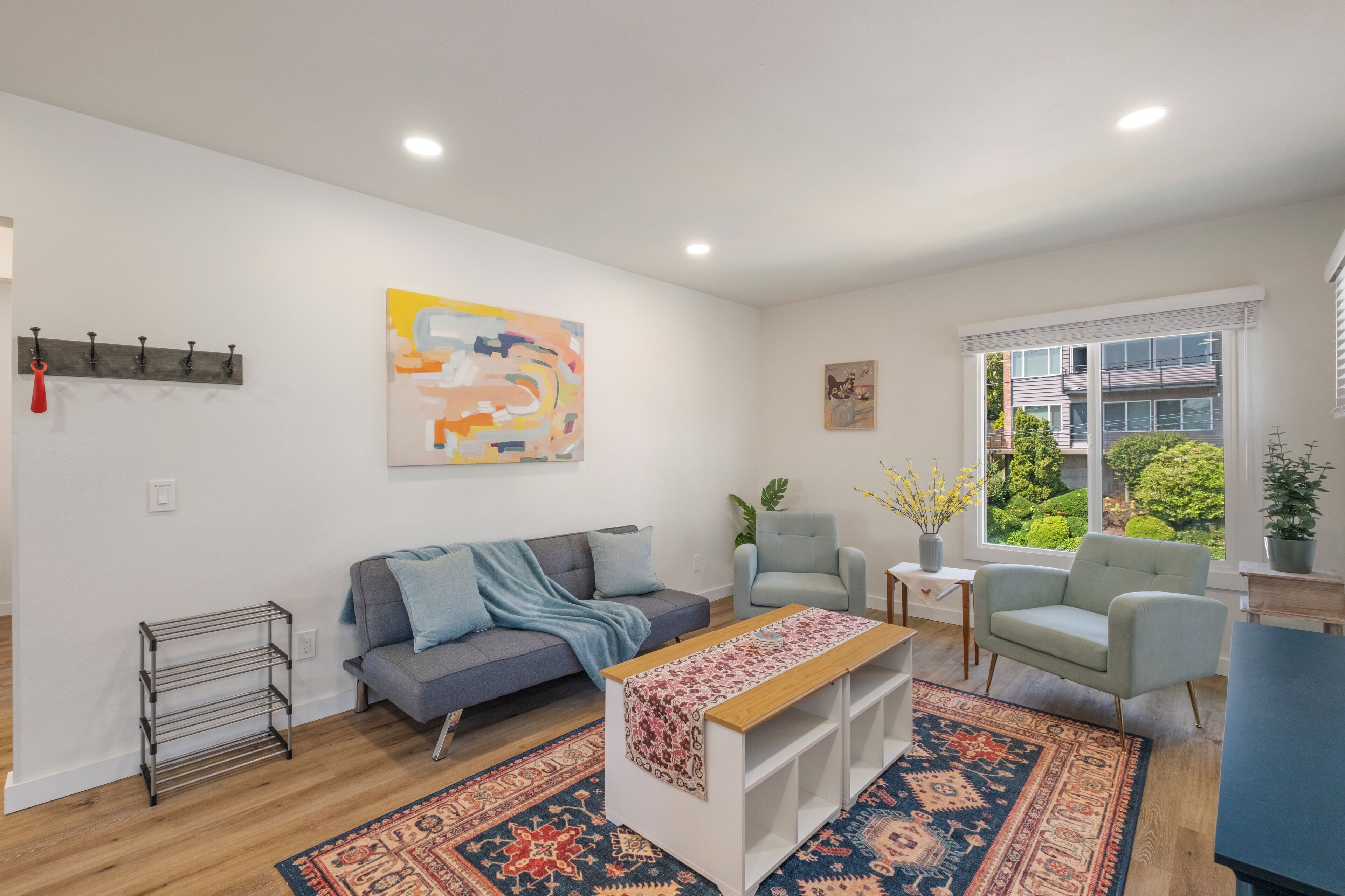 A modern living room with a grey sofa, a light blue armchair, a wooden coffee table, and a patterned rug.