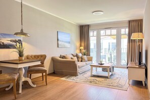 Ein Wohnzimmer mit einer Couch, einem Esstisch, Stühlen, einer Lampe und Blick durch eine Glastür.