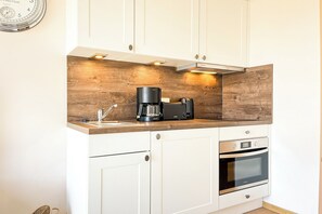 Eine Küche mit weißen Schränken, einer Holzarbeitsplatte, einer Kaffeemaschine und einem Backofen.