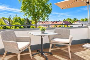 A balcony with two wicker chairs, a table, and a potted plant. - Baltischer Hof 52 Apartment (Ostseebad Boltenhagen)