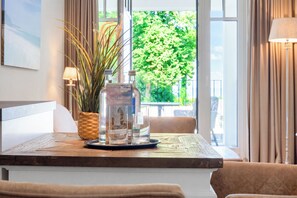 Une table en bois, une bouteille en verre et un panier tressé rempli de plantes.