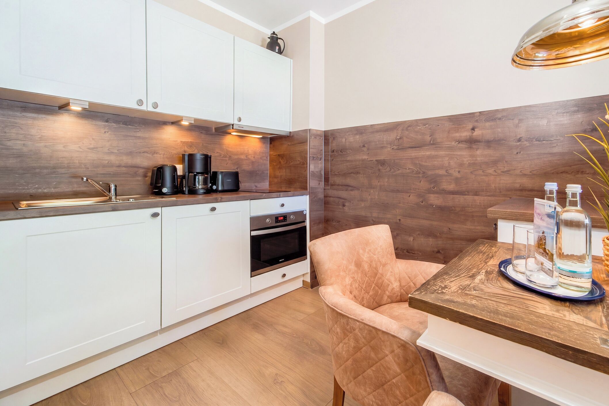 A modern kitchen with white cabinets, a coffee maker, and a built-in oven.