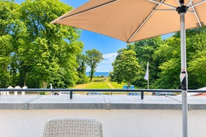 Ein Sitzbereich im Freien mit Blick auf einen angelegten Garten und das Meer.