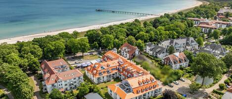 Ein Küstenwohngebiet mit Strand, einer Mole und Häusern mit roten Ziegeldächern.