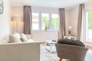 Ein modernes Wohnzimmer mit einer Couch, einem Sessel und einem kleinen Tisch mit einer Lampe.