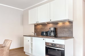 A modern kitchen with white cabinets, a built-in oven, and a coffee maker on the countertop. - Baltischer Hof apartment 45 (Ostseebad Boltenhagen)
