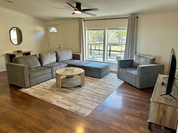 A living room with a sectional sofa, two armchairs, a coffee table, and a TV stand.
