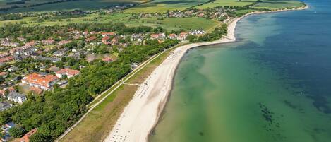 Vista aérea de un pueblo costero con playa, casas y una vista despejada del mar.
