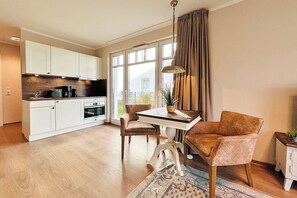 A modern kitchen with white cabinets, a dining table, and chairs. - Baltischer Hof apartment 18 (Ostseebad Boltenhagen)