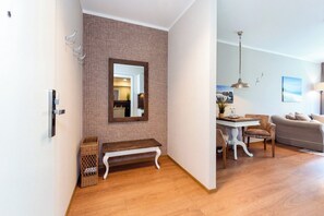 Ein modernes Wohnzimmer mit Holzboden, einem weißen Sofa, einem Esstisch mit Stühlen und einer Pendelleuchte.