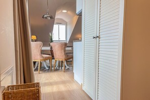 Ein Zimmer mit Essbereich, ausgestattet mit zwei Stühlen und einem Tisch, einem weißen Kleiderschrank und einer Pendelleuchte.