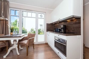 Eine moderne Küche mit weißen Schränken, einem eingebauten Backofen und einer Kaffeemaschine.