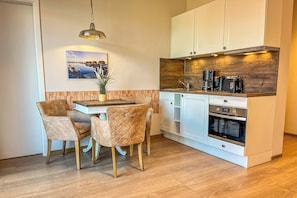 Eine kleine Küche mit weißen Schränken, einer Holz Arbeitsplatte und einem eingebauten Backofen.