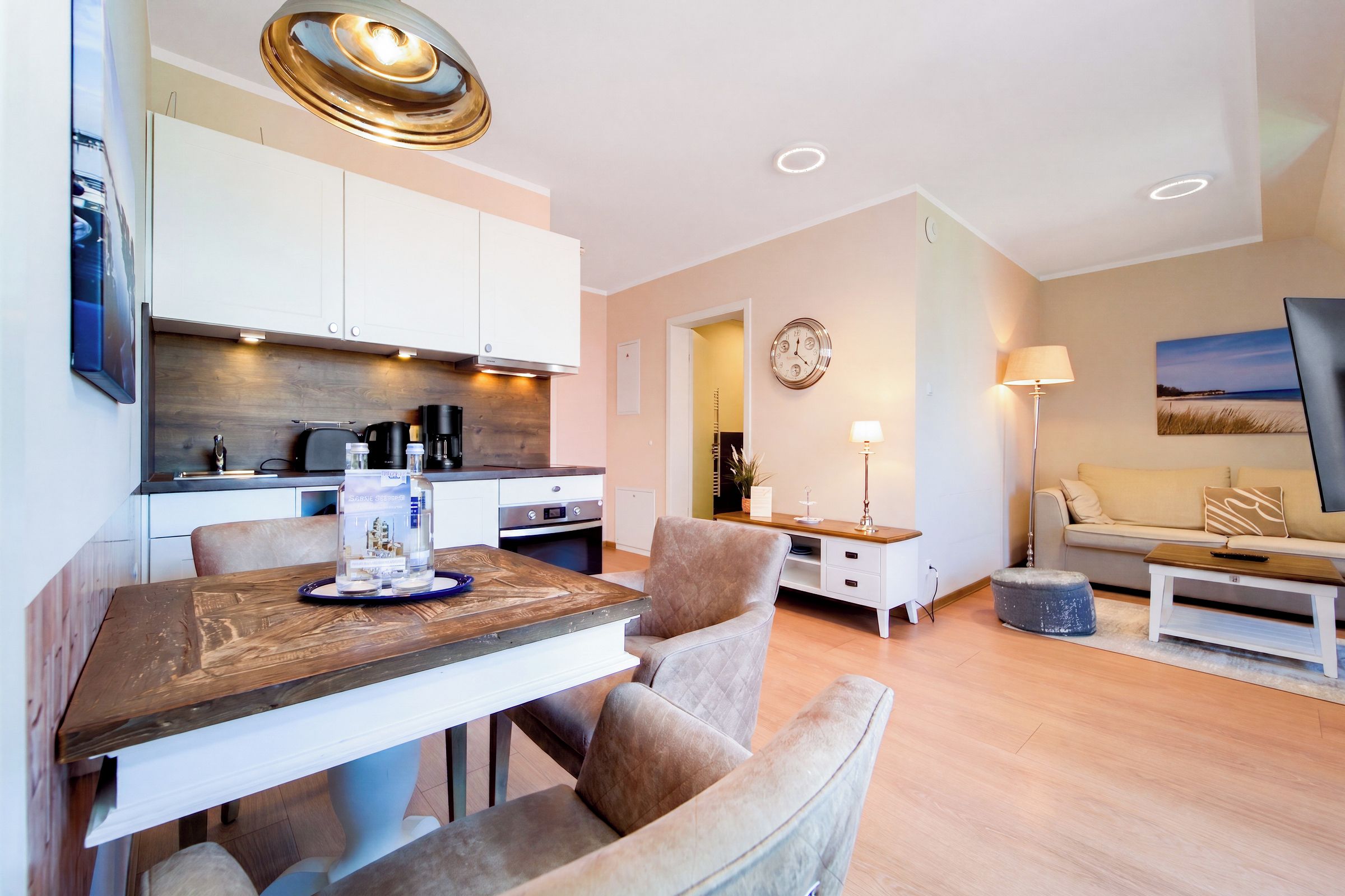 A modern living room with a dining area, a kitchen, and a sofa.