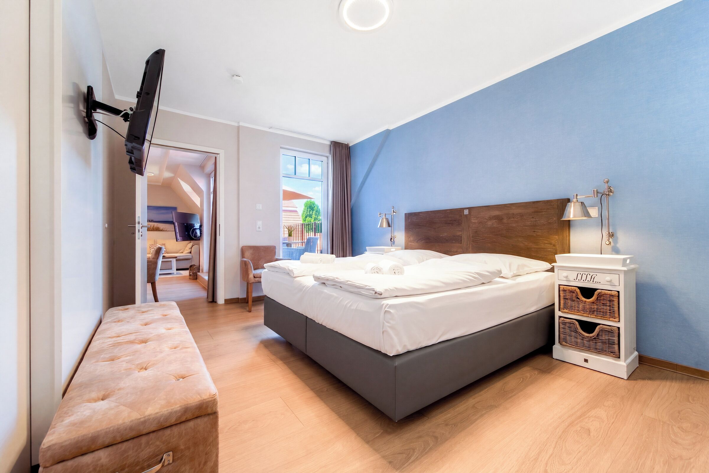 A modern hotel room with a bed, bedside table, and a bench.