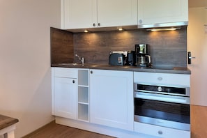 Eine moderne Küche mit weißen Schränken, einem eingebauten Backofen und einer Kaffeemaschine.