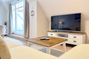 A modern living room with a TV, wooden coffee table, and a sofa. - Baltischer Hof 62 Apartment (Ostseebad Boltenhagen)