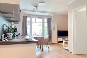 Eine moderne Küche mit Spüle, einem Essbereich mit Stuhl, einem Fernseher und einem großen Fenster mit Vorhängen.