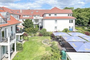 Ein Innenhof mit Rasenfläche, Gartenmöbeln und Sonnenschirmen.