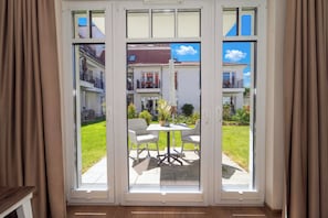 Eine Glastür öffnet sich zu einer Terrasse mit Tisch und Stühlen.