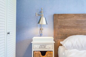 Une chambre à coucher avec une tête de lit en bois, une table de chevet blanche avec une lampe et un panier en osier.