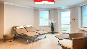 A room with two reclining chairs, a small table, and a potted plant. There are two windows and a door. - Baltischer Hof apartment 27 (Ostseebad Bolgenhagen)
