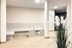 Ein modernes Badezimmer mit Sitzbank, zwei Waschbecken und einer Zierpflanze.