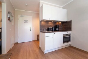 Eine moderne Küche mit weißen Schränken, einem eingebauten Backofen und einer Kaffeemaschine.