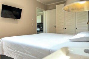 Ein Schlafzimmer mit einem Bett, einem an der Wand montierten Fernseher und einem Kleiderschrank mit Schiebetüren.