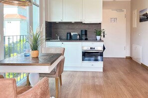 Eine moderne Küche mit weißen Schränken, einem Holztisch und einem Blumentopf.