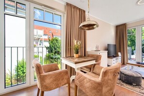 Un salon moderne avec un coin repas, de grandes fenêtres et une vue sur l’extérieur.