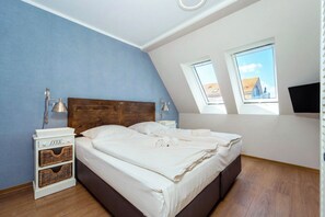 Ein Schlafzimmer mit einem Bett, zwei Nachttischen, einem Fenster und einem Fernseher.