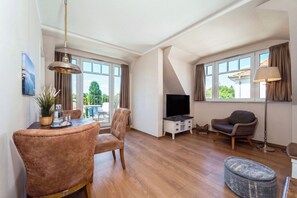 A living room with a dining table, chairs, a TV, and a lamp. - Baltischer Hof apartment 58 (Ostseebad Boltenhagen)