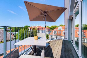 A balcony with a table, chairs, a potted plant, and a large umbrella. - Baltischer Hof apartment 67 (Ostseebad Boltenhagen)