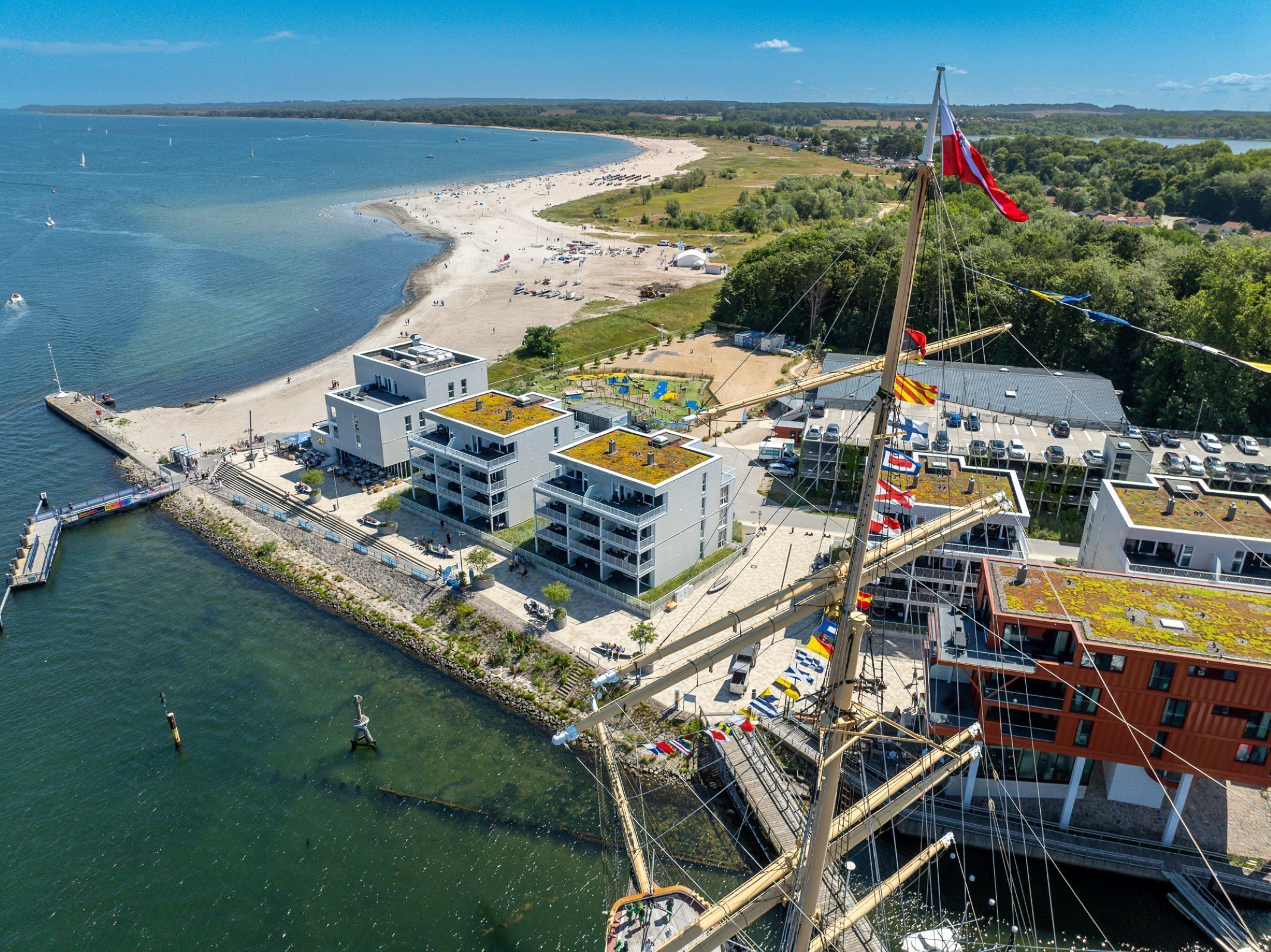 Un hotel frente al mar con varias construcciones, una playa y un muelle.