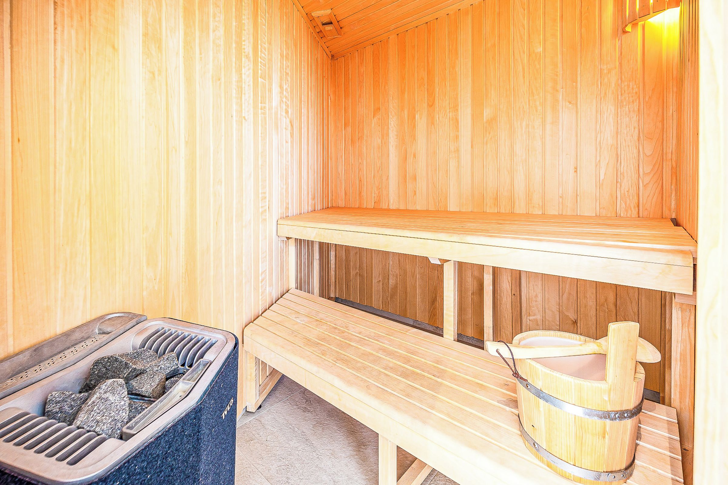 A sauna room with a bench, a foot bath, and a wooden bench.