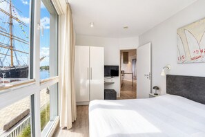 Ett hotellrum med ett stort fönster, en säng, en garderob och ett skrivbord.