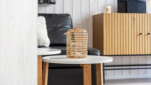 A modern living room with a round white table, a black leather sofa, and a wooden cabinet. - Vacation home Freibeuterweg 13 (Lübeck-Travemünde)