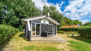 Ein modernes Haus mit Terrasse, großen Fenstern und einer Satellitenschüssel.